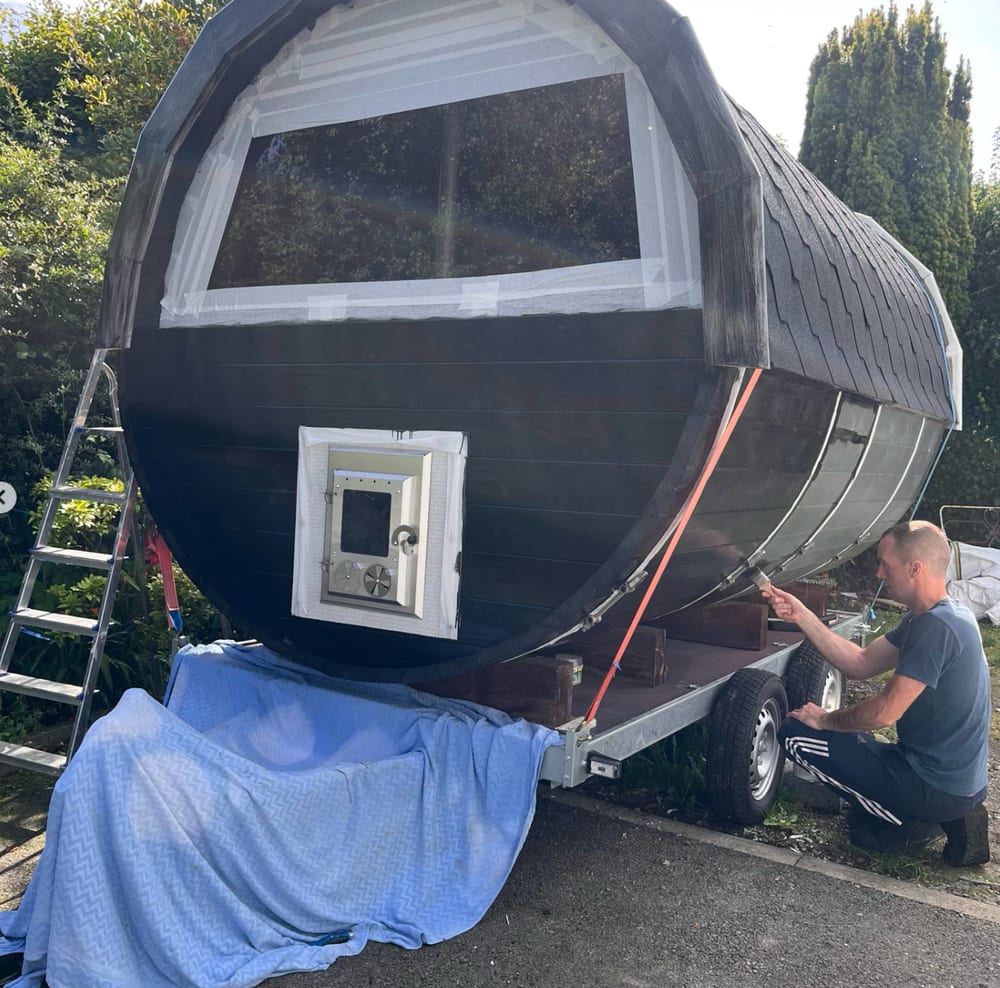 Shane painting the sauna black, windows and door taped off